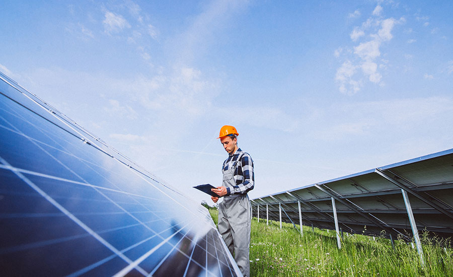 Un ouvrier travaillant sur le terrain, entouré de panneaux solaires de grande taille