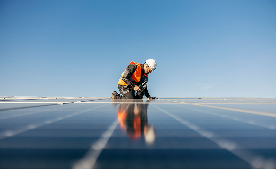 Un ouvrier travaillant sur le terrain, entouré de panneaux solaires de grande taille